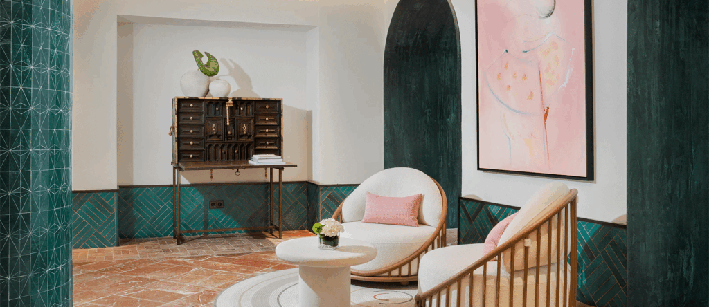 El Fuerte modern hotel lounge corner with round armchairs, marble coffee table, abstract wall art, and decorative accents in Mediterranean style.