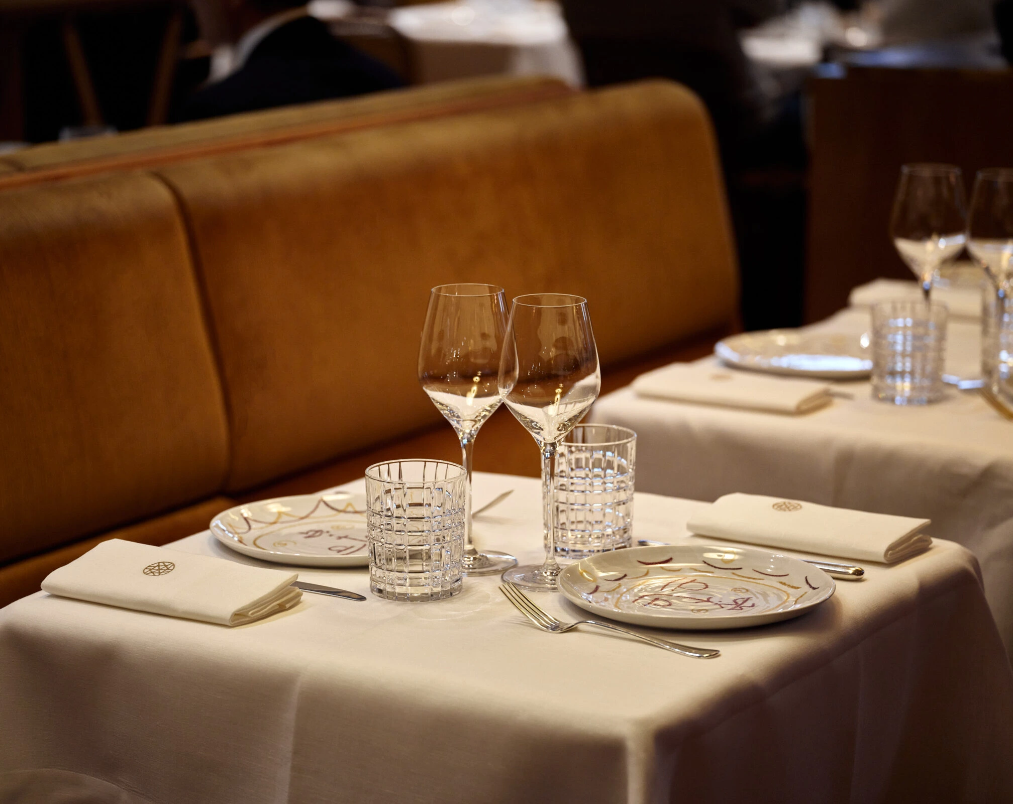 Elegant restaurant table setting with crystal glasses, fine china plates, and white linen tablecloths likely in one of the Michelin-Starred Restaurants in Paris