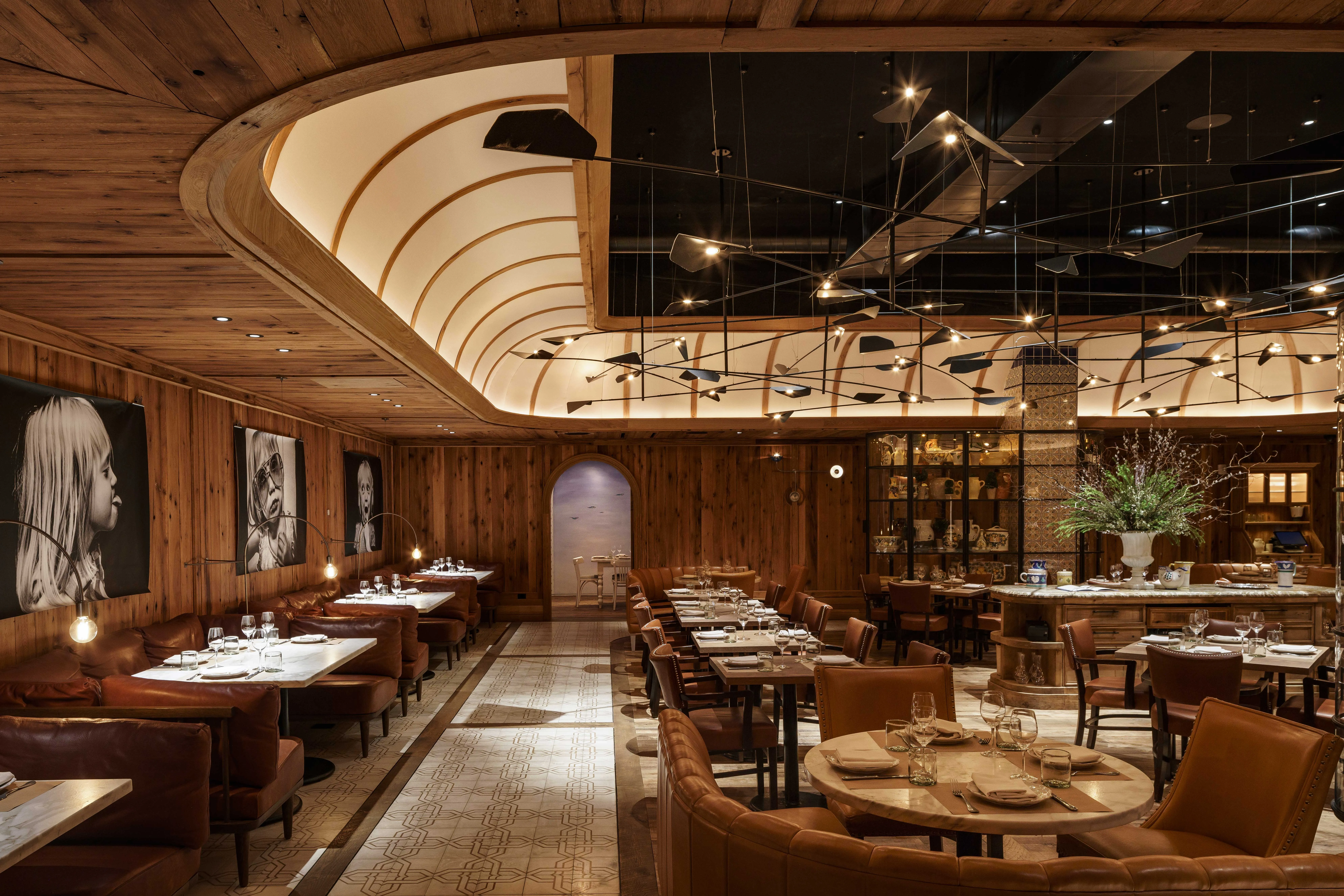 Elegant luxury restaurant interior designed by Studio Munge, featuring curved banquette seating, natural wood textures, sculptural ceiling lighting, and a warm, immersive fine dining atmosphere.