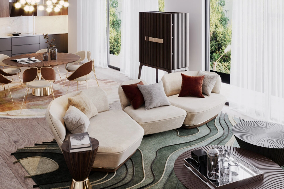 Elegant open-plan living and dining area featuring a curved cream sofa, sculptural coffee tables, a green patterned rug, sheer curtains, and a round dining table with modern chairs in the background.