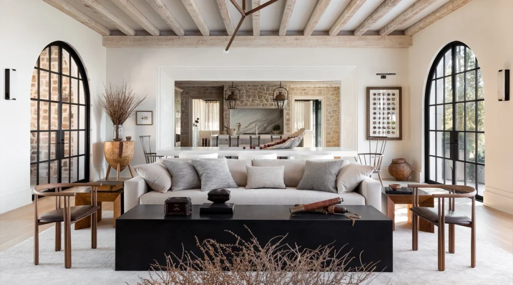 Mediterranean luxury living room with stone walls, arched windows, and neutral furnishings, combining international interior design with regional craftsmanship.