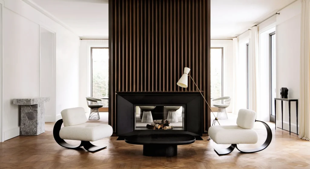 Architectural minimalist living room featuring sculptural armchairs, a monolithic fireplace, and refined wood detailing, emphasizing symmetry and spatial balance.
