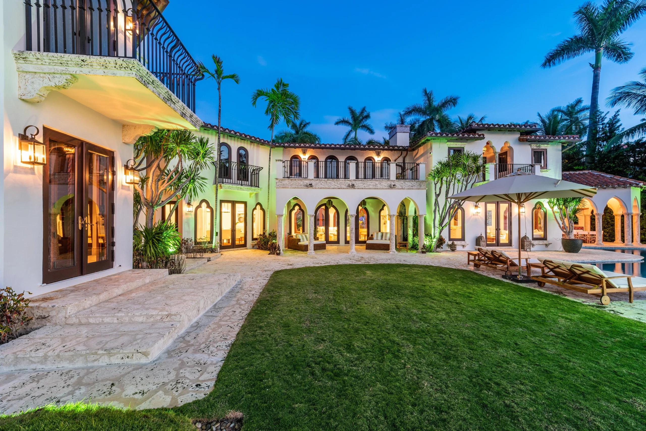 Modern Mediterranean living space with symmetrical arched windows, limestone walls, minimalist furnishings, and a neutral color palette emphasizing craftsmanship and architectural balance.