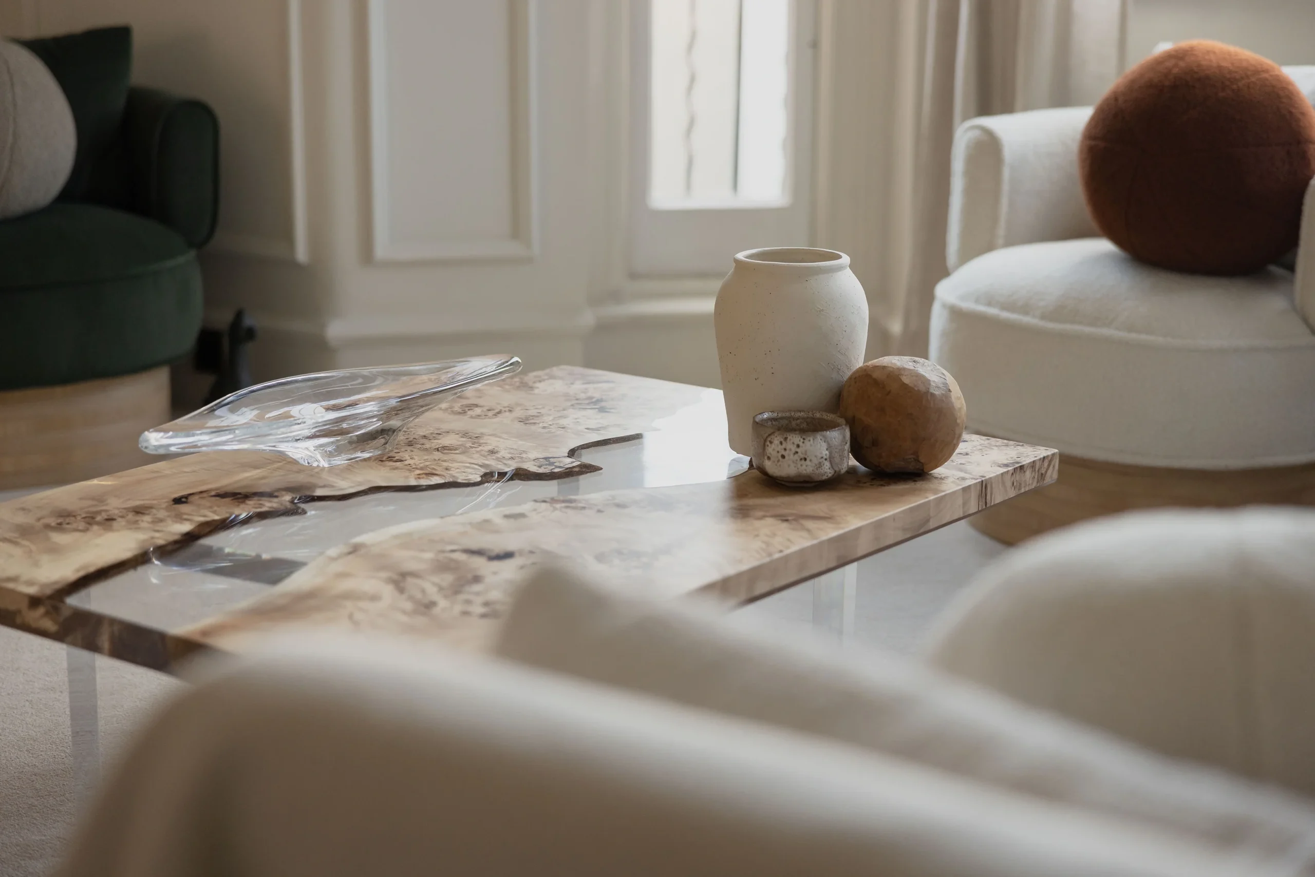 Contemporary living room detail featuring a sculptural marble coffee table styled with ceramic objects and soft neutral seating in a refined modern interior