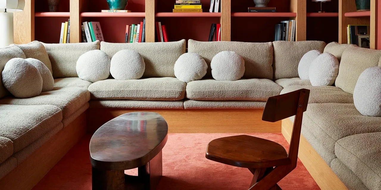 Curved bouclé sectional sofa in a sophisticated reading room, combining plush upholstery, warm wood shelving, and modern residential interior design.