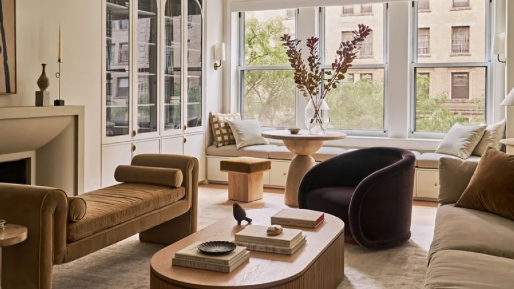 Luxury interior design showcasing Manhattan penthouse interiors with panoramic skyline views and double-height living spaces alongside refined Paris pied-à-terre design in a classic Haussmann apartment, featuring bespoke furniture, natural stone dining tables, artisan-crafted seating, and elegant architectural details blending modern sophistication with historic character.