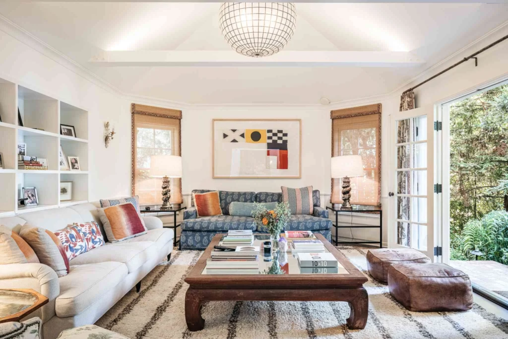 Bright eclectic living room featuring an antique wooden coffee table alongside contemporary sofas and modern artwork