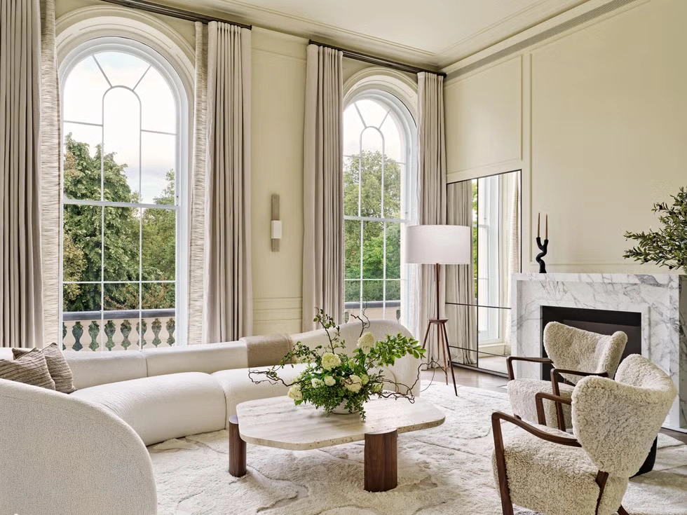 Neutral living rooms showcasing layered neutral interior design with textured linen and bouclé seating, warm wood furniture and paneling, sculptural coffee tables, soft area rugs, marble fireplaces, and refined metal lighting accents—demonstrating depth and dimension in contemporary neutral interiors.