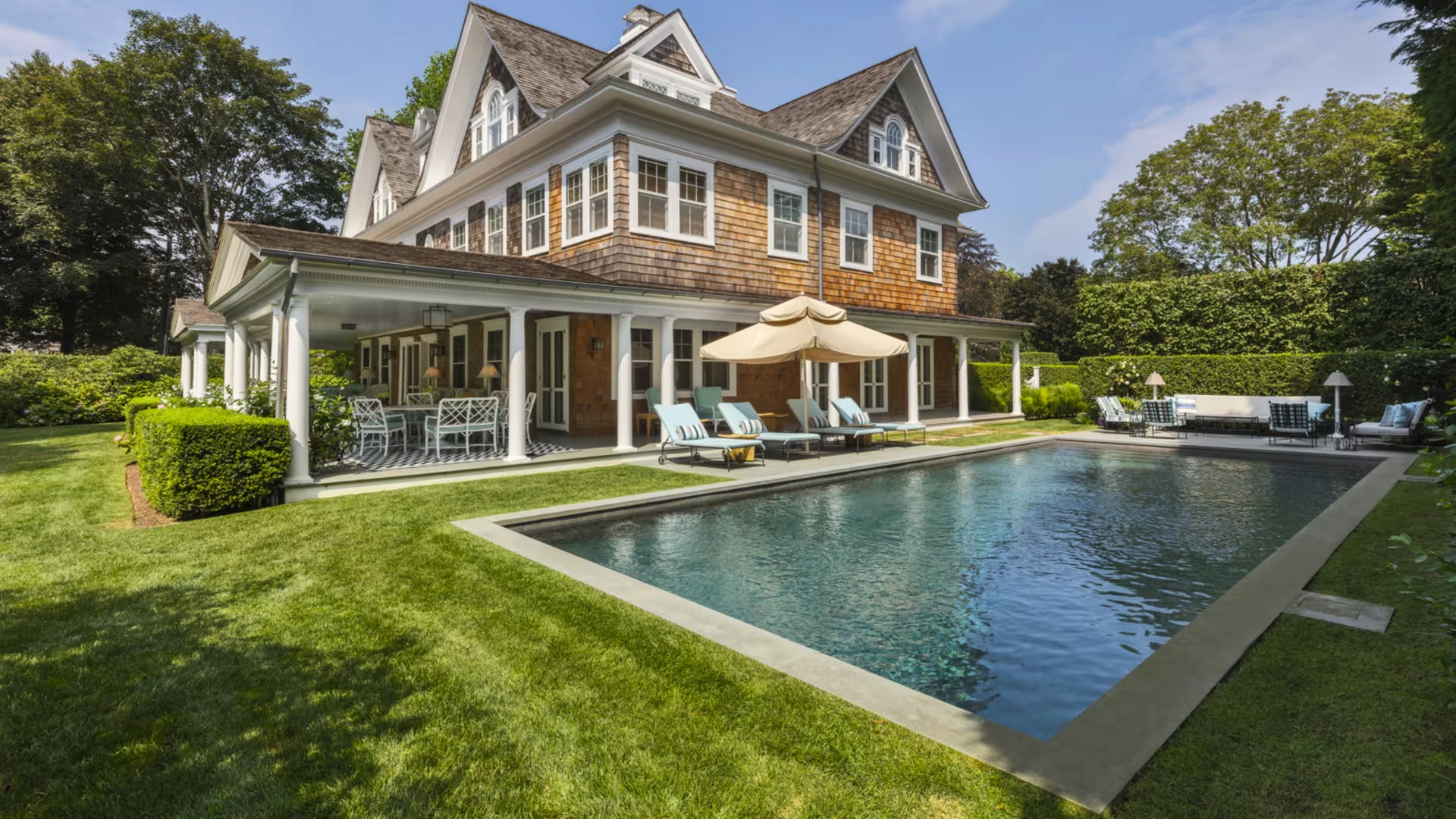 Luxury Hamptons-style East Coast summer home showcasing open-plan coastal interiors, cedar-shingle architecture, landscaped gardens, and a refined infinity pool setting that embodies timeless luxury coastal living.