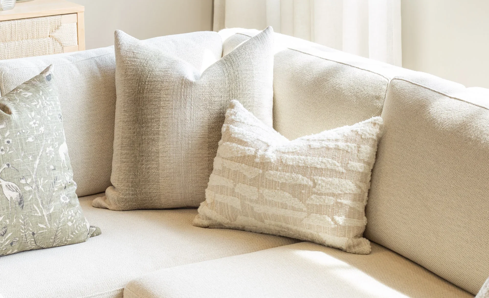 legant neutral sofa upholstered in textured luxury fabric with layered cushions, highlighting contemporary luxury upholstery care in a softly lit interior